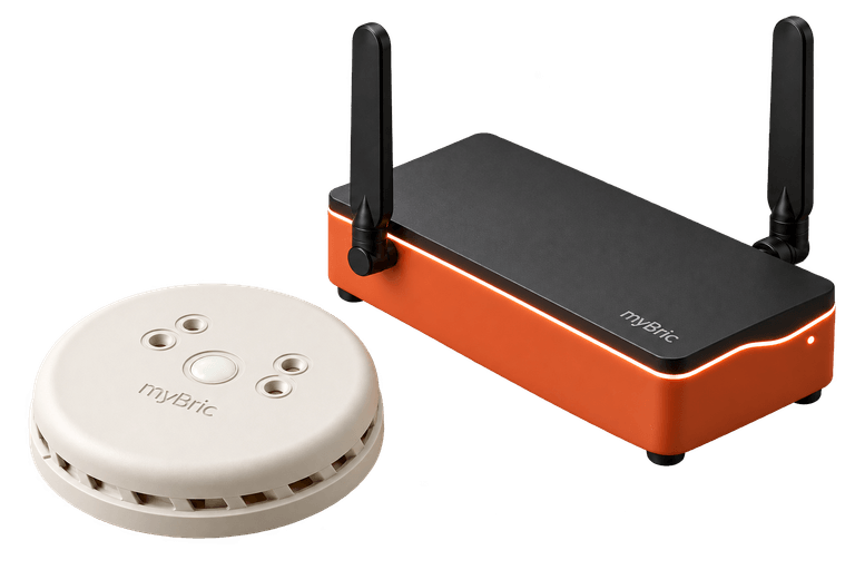 Vue d’artiste du hub myBric, coque terracotta et dessus noir, antennes déployées, à côté du module d’ambiance rond blanc cassé à lentille opale.
